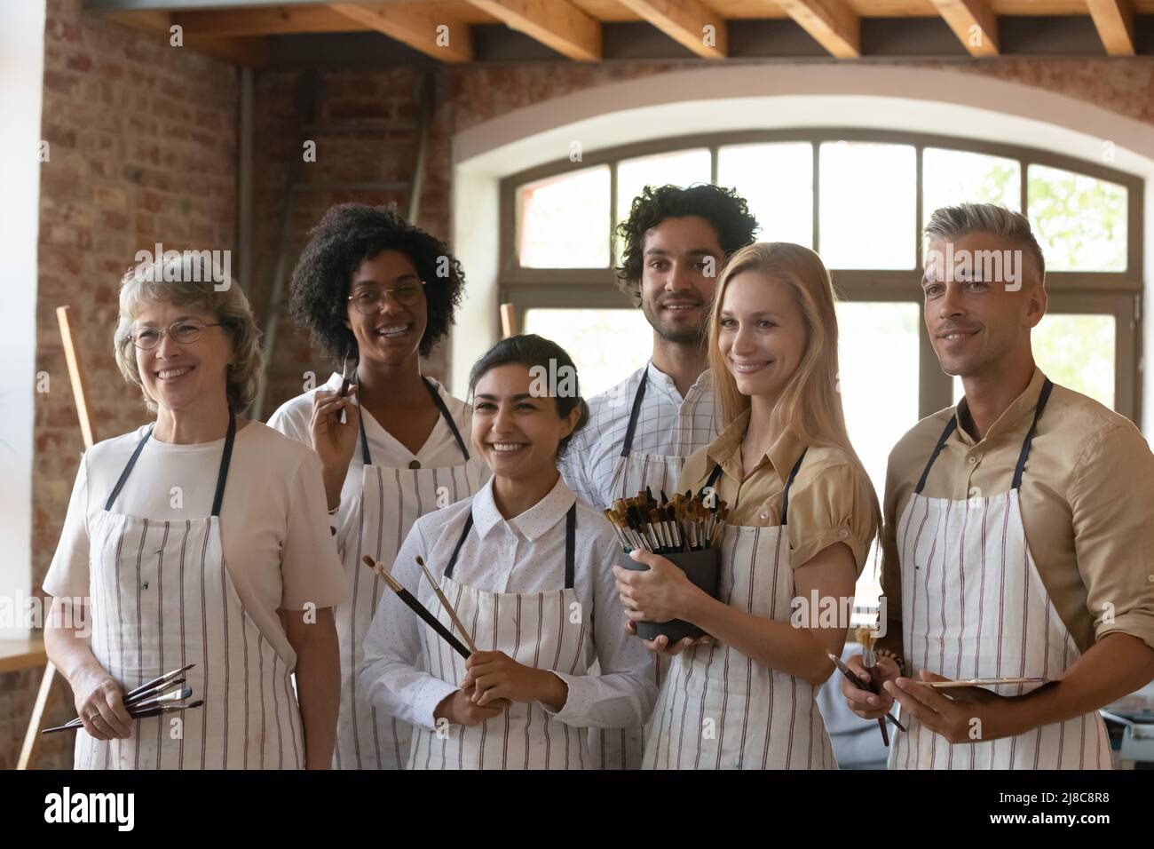 Eine Gruppe von Leuten, die Pinsel halten, posieren in der Werkstatt des Kunststudios Stockfoto