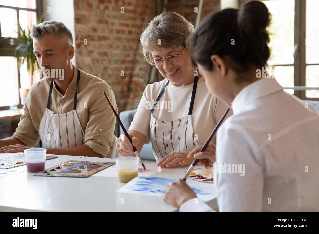 Drei verschiedene Schüler der Kunstschule malen mit Acrylfarben auf Papier Stockfoto