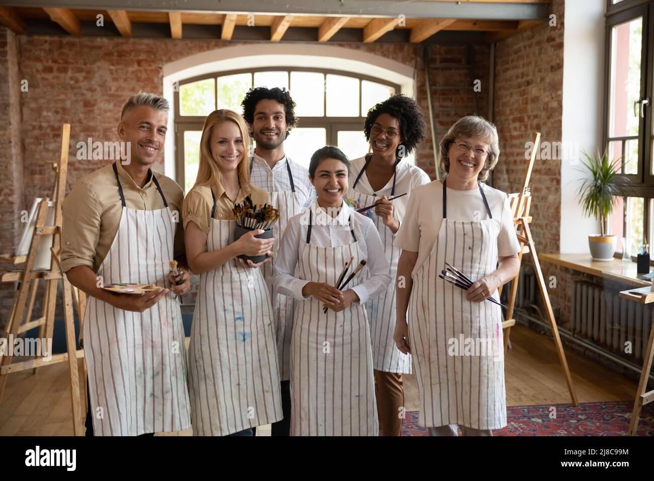 Gruppe von multiethnischen Menschen, die im Atelier der Kunstschule Pinsel in der Hand halten Stockfoto