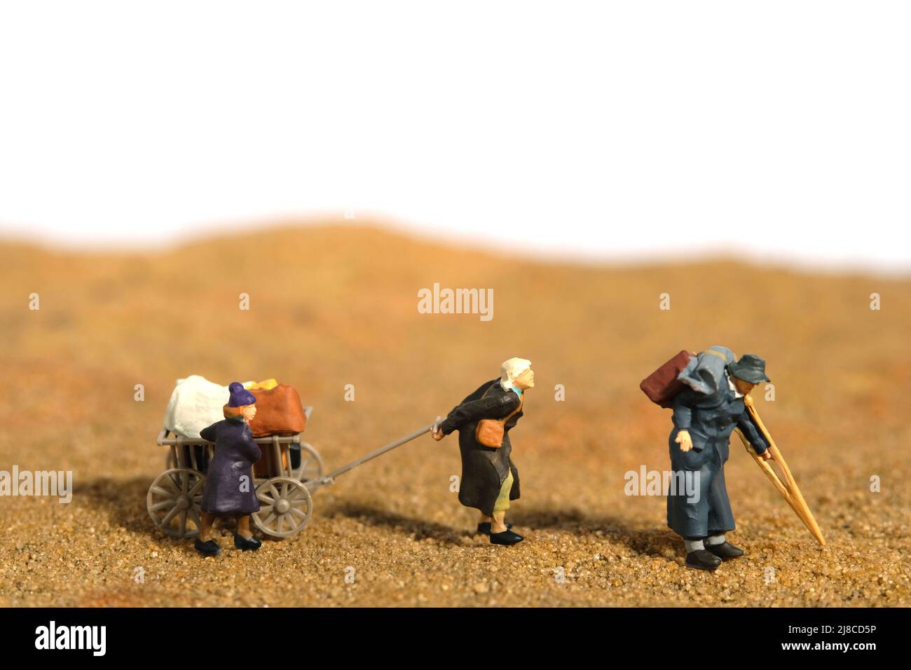 Miniatur Menschen Spielzeug Figur Fotografie. Ein älteres Paar mit einem Enkelkind, der als Flüchtling unterwegs war, bewegte sich mitten in der Wüste und ging zum Flüchtlingslager Stockfoto