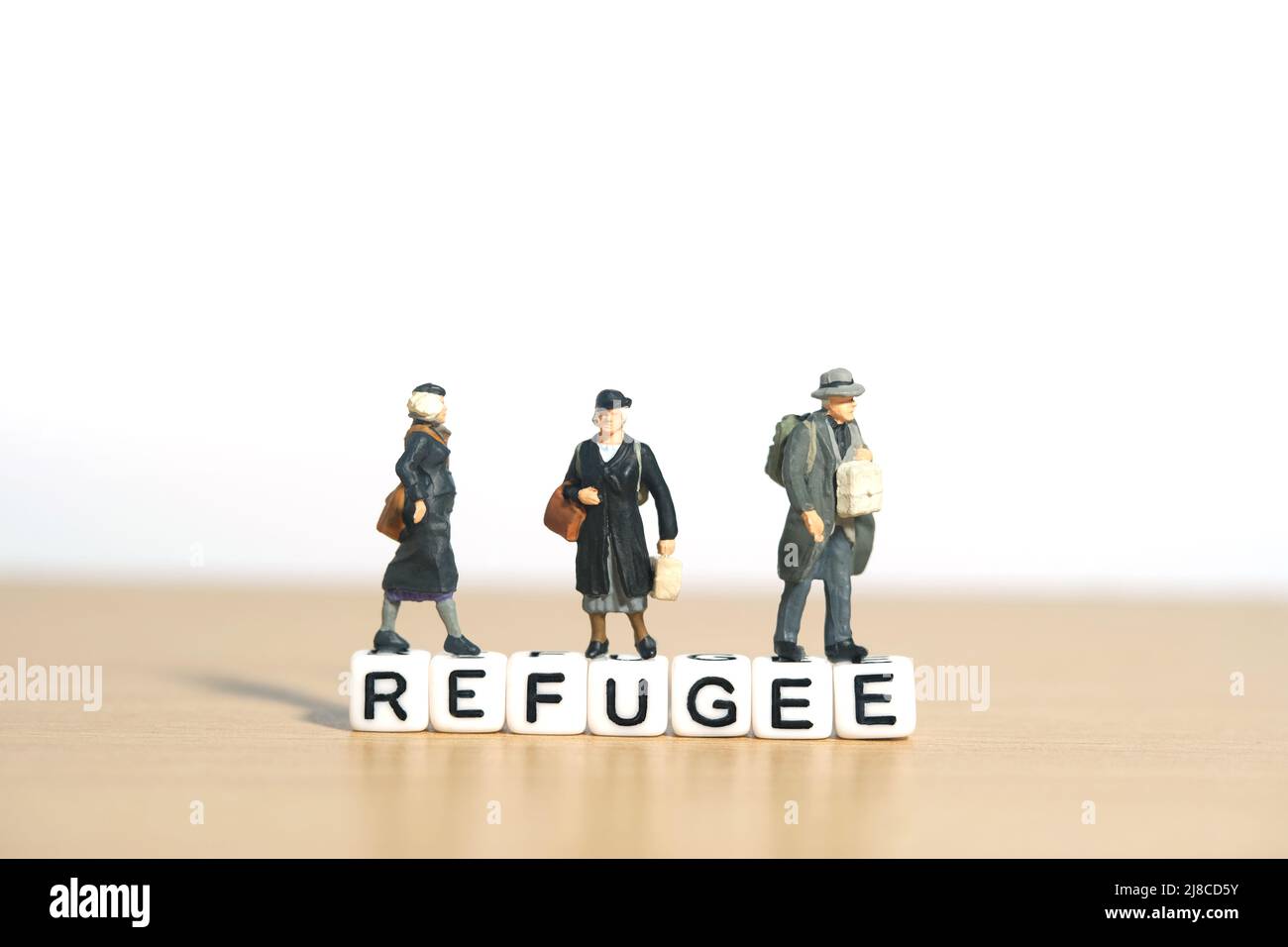 Miniatur Menschen Spielzeug Figur Fotografie. Eine Gruppe von Personen, die über dem Wortwürfel des Flüchtlings stehen. Bildfoto Stockfoto