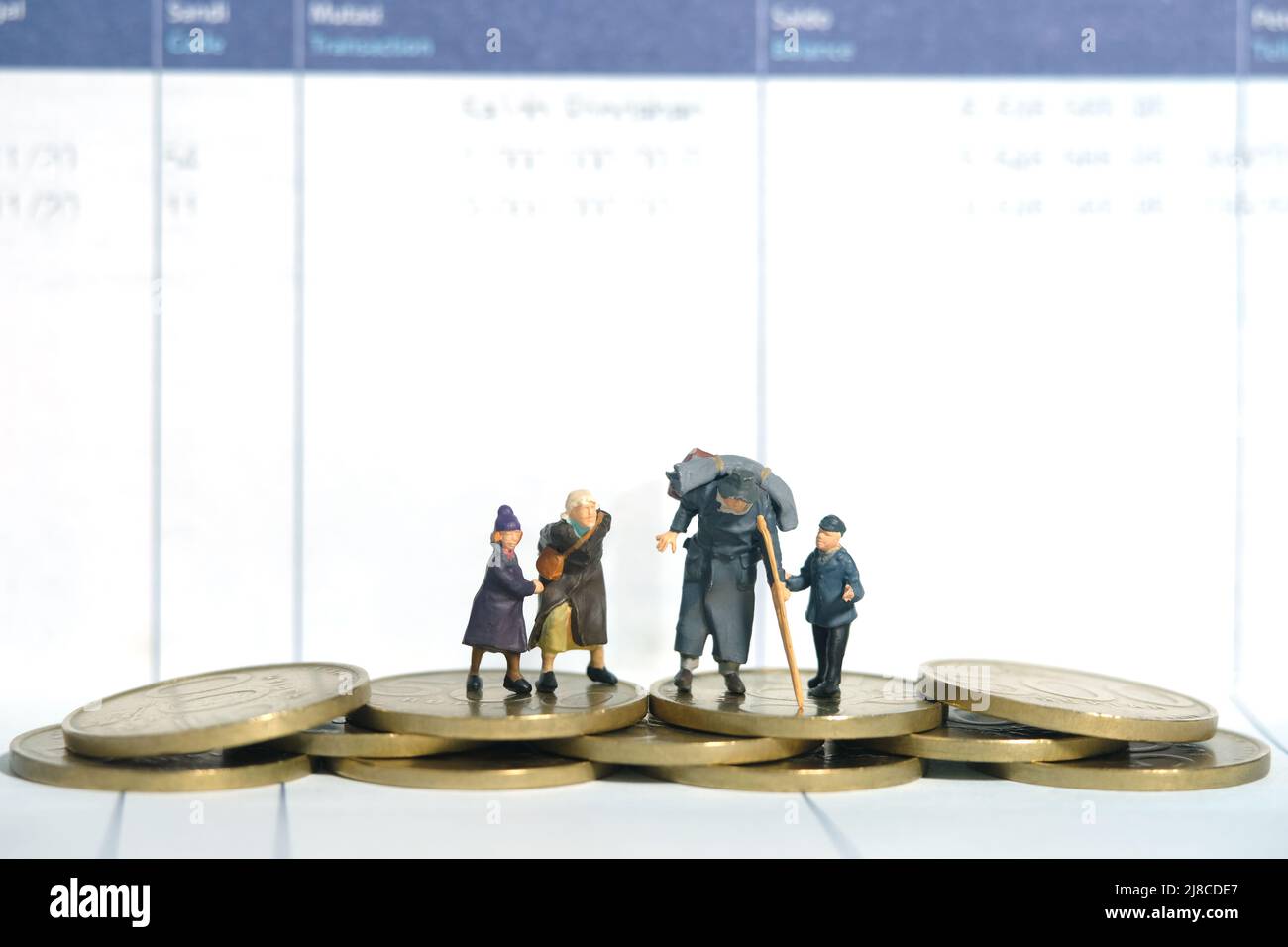 Miniatur Menschen Spielzeug Figur Fotografie. Eine Gruppe von armen Großeltern, Oma und zwei Enkelkindern, die über Münzen und Bankkonten stehen. Im Stockfoto