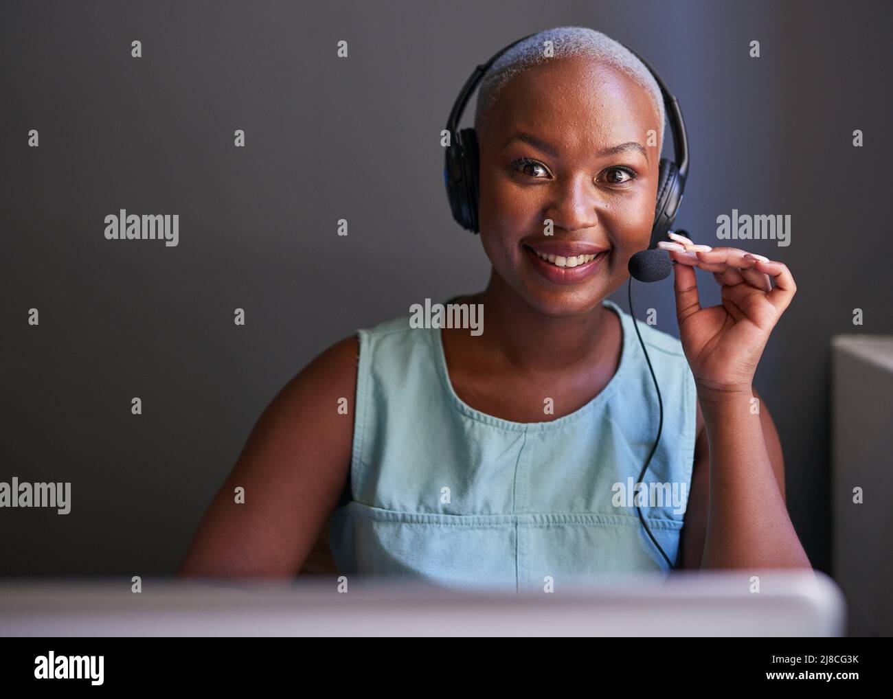 Ein schwarzer Callcenter-Agent lächelt während eines Anrufs mit einem Headset Stockfoto