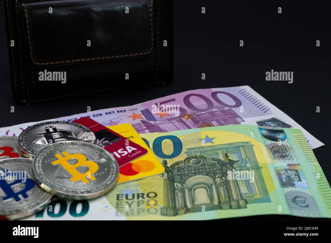 Goldene Bitcoin-Münzen lagen auf Banknoten und Kreditkarten von 100 Euro und 500 Euro. Goldbitcoin auf hundertfünfhundert Euro-Banknoten. Stockfoto