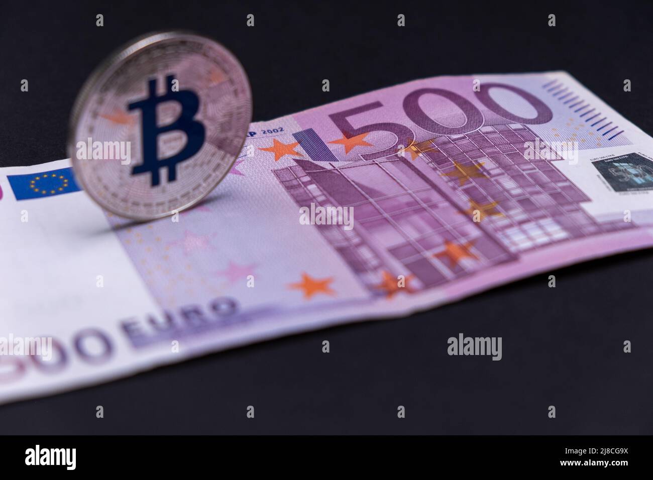 500-Euro-Banknote mit entkoffter Silber-Bitcoin-Münze lag darüber. 500 Euro Banknote mit Silberbitcoin in defokussiert und perspektivisch. Stockfoto