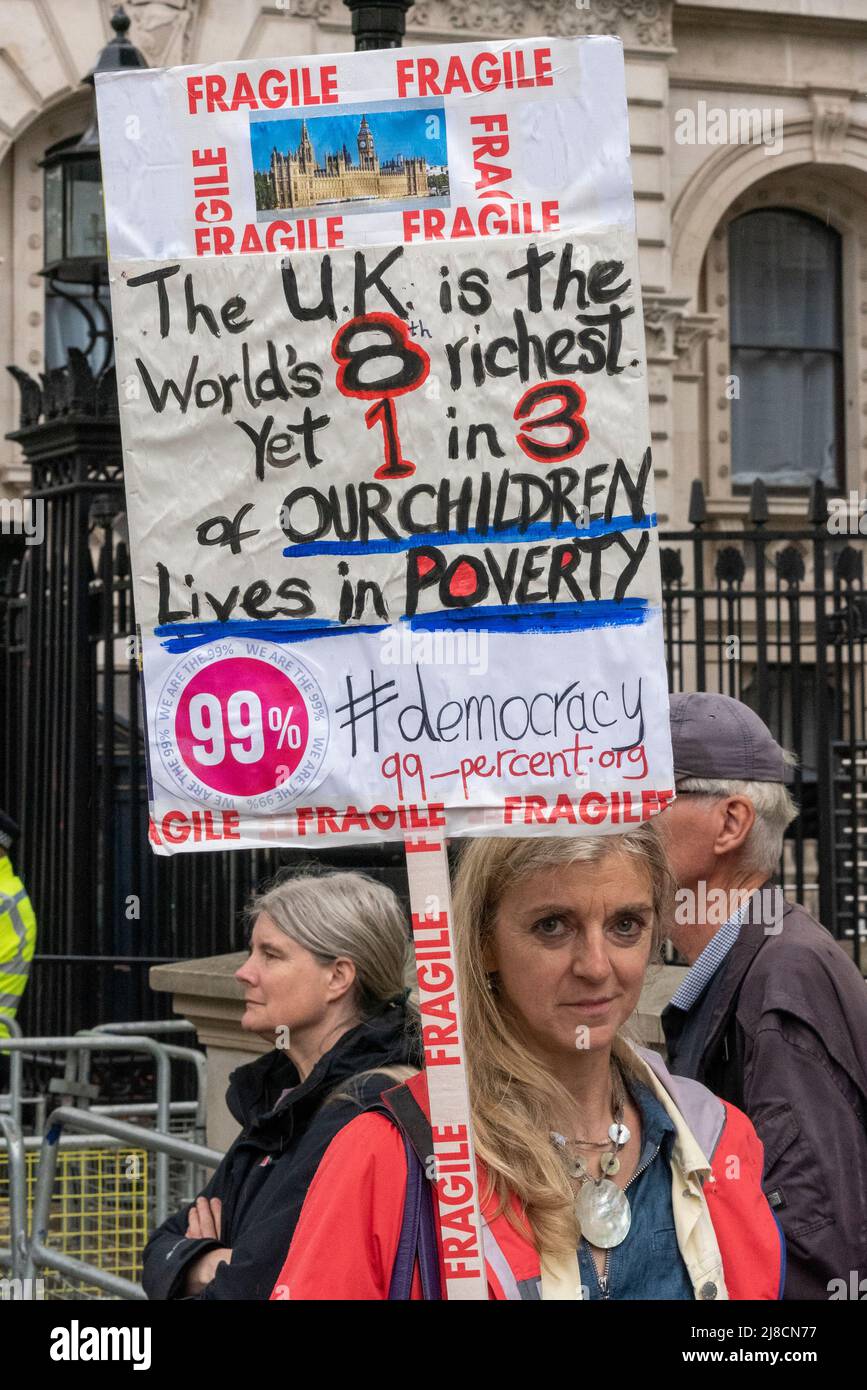 Whitehall, Westminster, London, Großbritannien. 15.. Mai 2022. Im Regen vor der Downing Street in Whitehall findet ein Protest gegen angebliche Lügen, Inkompetenz und Korruption des Premierministers Boris Johnson und der konservativen Regierung statt. Die Demonstranten sind wütend auf die Bilanz der Regierung in Bezug auf den Brexit, die Covid-Pandemie und die Lebenshaltungskrise und fordern Johnsons Rücktritt und höhere Standards von den Abgeordneten. Plakat zur Kinderarmut Stockfoto