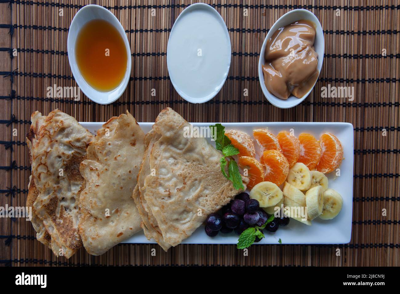 Gesundes Frühstück mit Pfannkuchen. Hausgemachte amerikanische Pfannkuchen mit Obst, Beeren und Honig. Draufsicht flach lag . Stockfoto