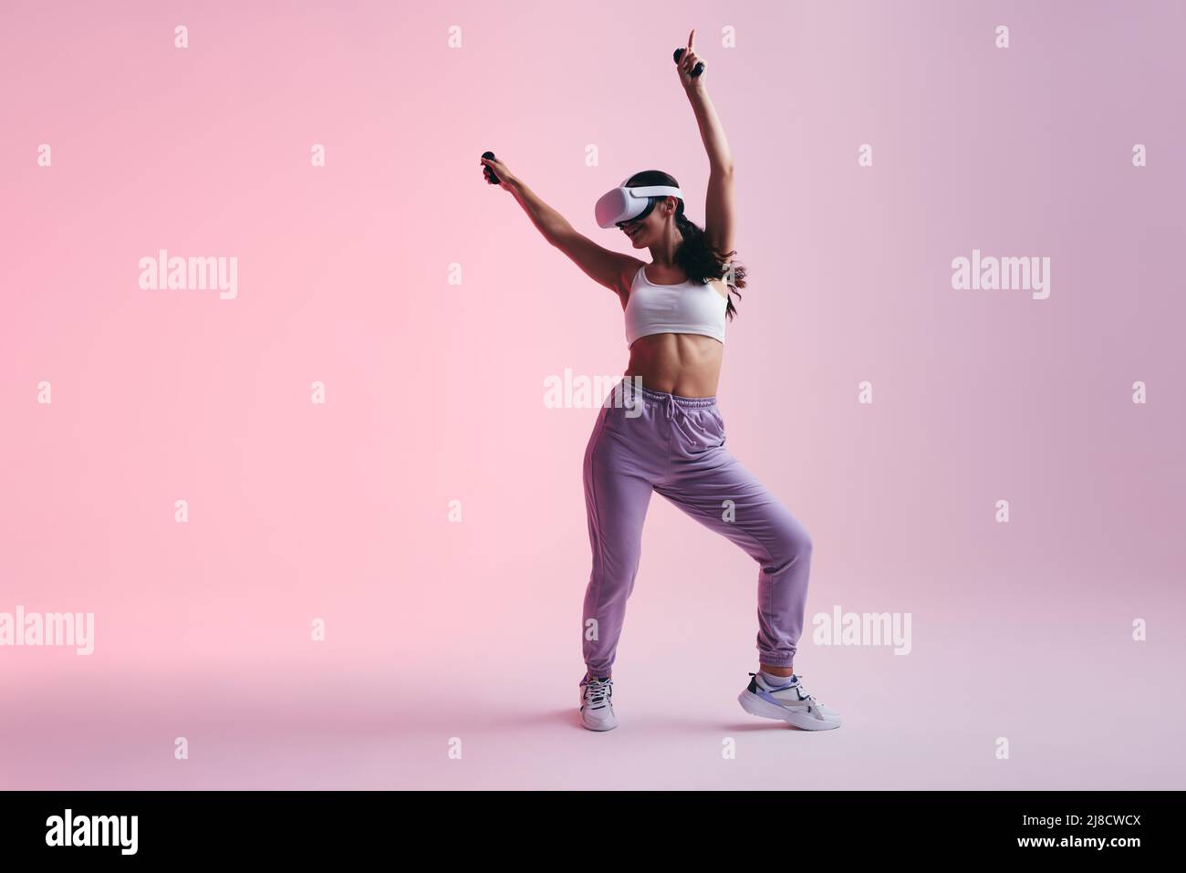 Fröhliche junge Frau, die mit einem Virtual Reality-Headset tanzt. Glückliche junge Frau genießt ihre virtuelle Realität Erfahrung. Frau mit Spaß whil Stockfoto