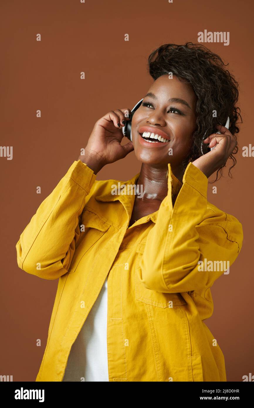 Porträt einer glücklichen jungen schwarzen Frau, die ihr Lieblingslied in Kopfhörern hört Stockfoto