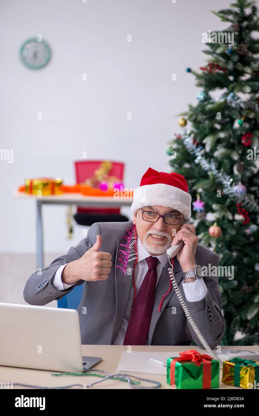 Ein alter Geschäftsmann feiert Weihnachten im Büro Stockfoto