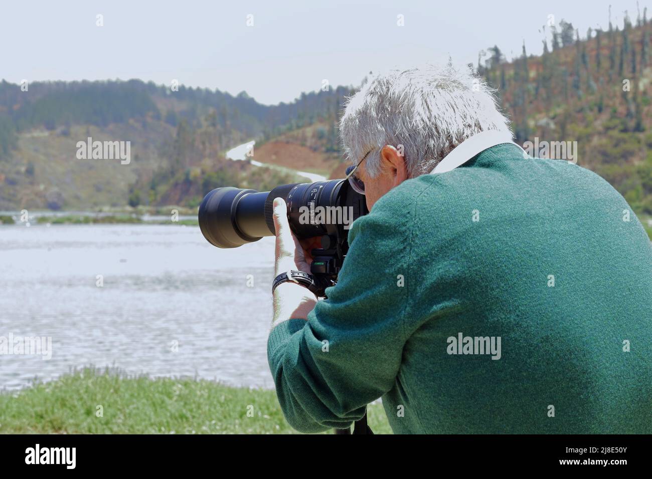 Der Mann fokussiert sein Teleobjektiv, während er ein Bild fotografiert Stockfoto