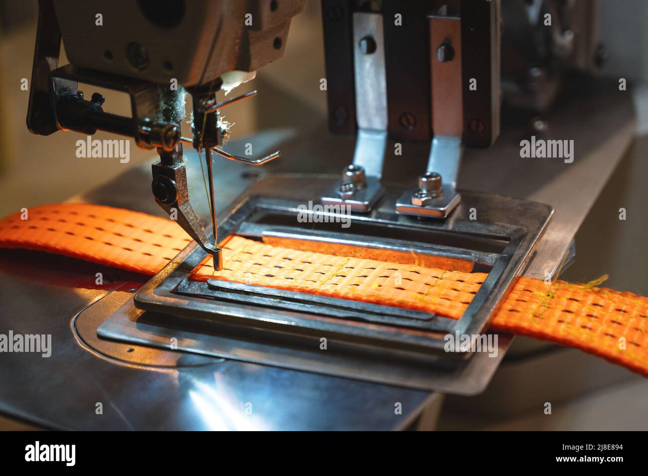 Nähmaschine arbeitet mit orangefarbenem Schleppgurt im Laden Stockfoto