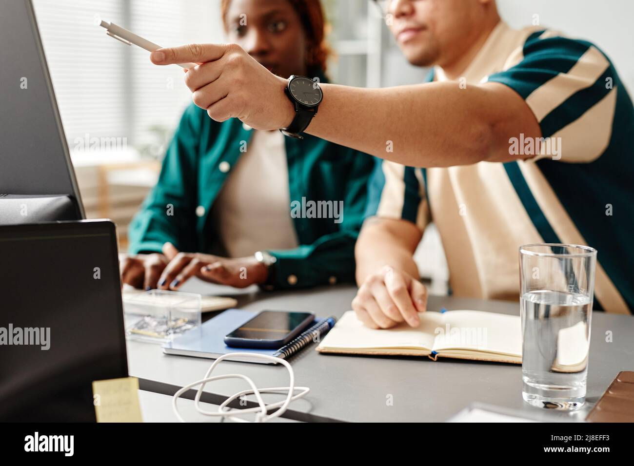 Nahaufnahme von zwei Softwareentwicklern oder QS-Ingenieuren, die Code überprüfen und auf den Computerbildschirm zeigen, Platz kopieren Stockfoto