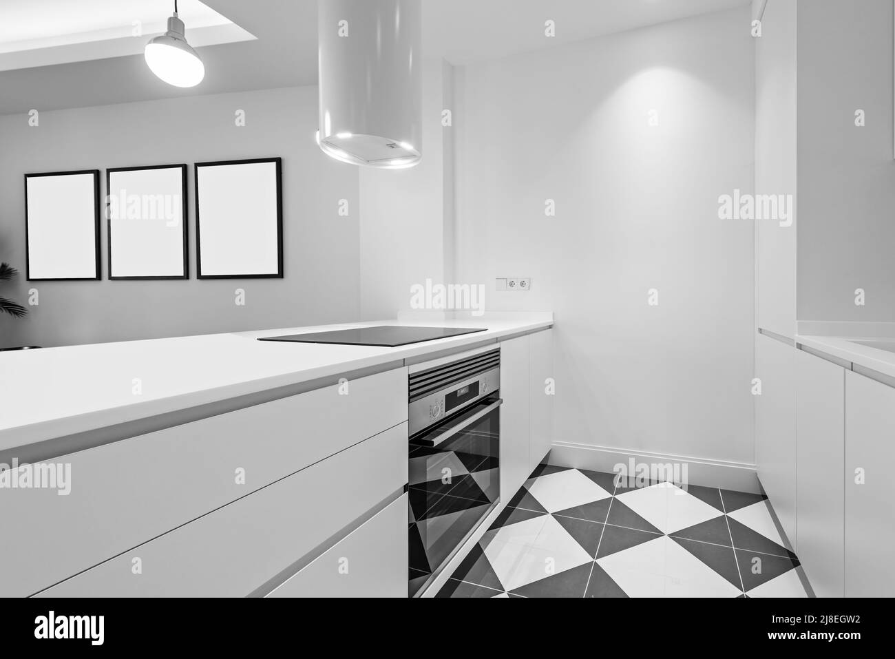 Offene Küche mit weißen Möbeln mit integrierten Geräten, Keramikböden und weißem runden Dunstabzugshaube Stockfoto
