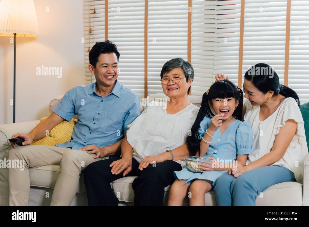 Asiatische Multi-Generationen-Familie von Vater, Mutter, Tochter und Großmutter Fernsehen auf dem Sofa im Wohnzimmer Stockfoto