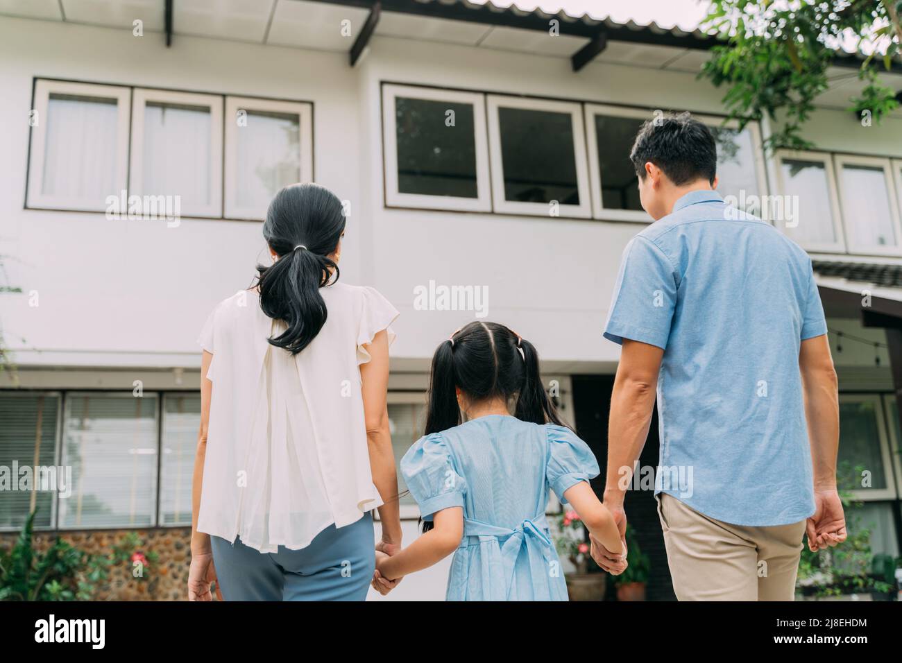 Asiatische Familie von Vater, Mutter und Tochter, die die Hände zusammenhält und geht, um einzuziehen. Immobilienkauf und Familienumstieg im Konzept Stockfoto