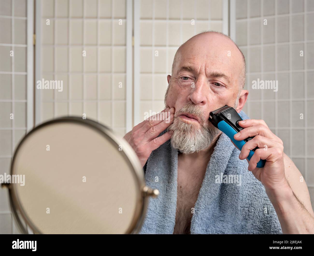 Kahlköpfiger und bärtiger älterer Mann verwendet elektrische Rasiermesser,  um seine Küken zu rasieren und Bart zu trimmen, Pflege und Selbstpflege für  Männer Konzept Stockfotografie - Alamy