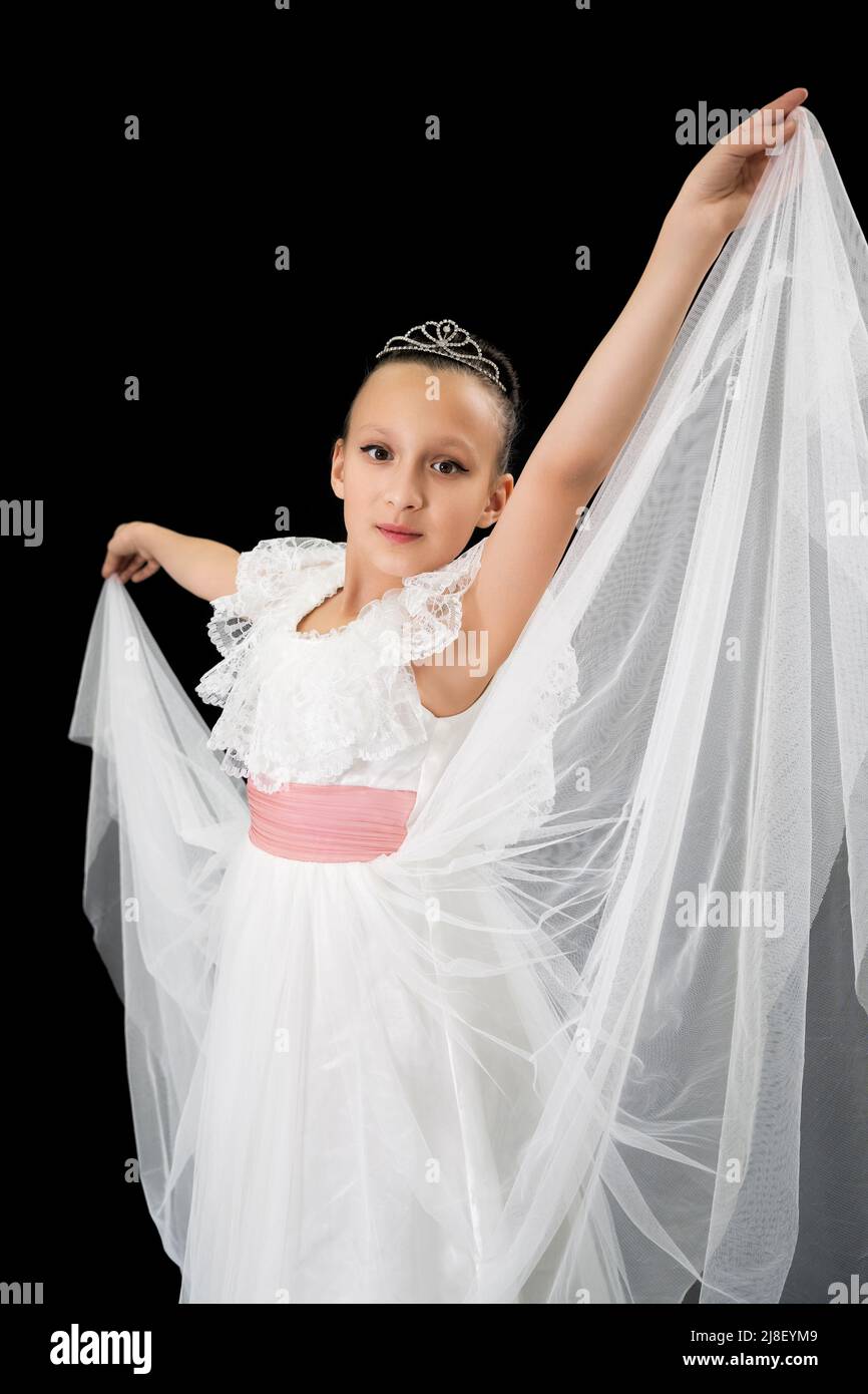 Mädchen Ballerina mit Diadem auf dem Kopf in weißen langen Kleid theatralischen Tanz auf schwarzem Hintergrund gekleidet. Teil der Fotoserie Stockfoto