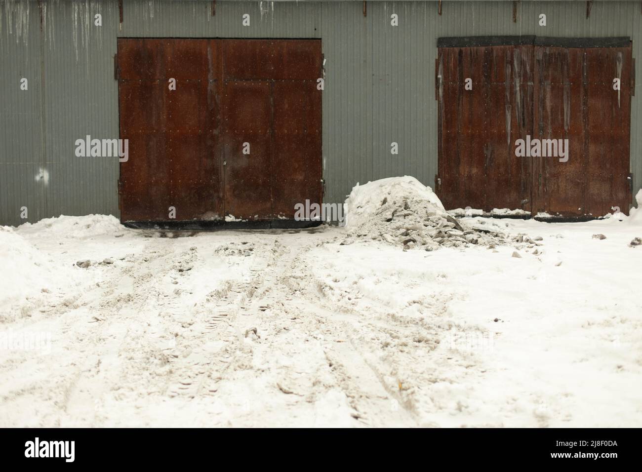 Garagentor im Winter. Eingang zum Lager. Produktionsraum. Rostige Türen. Stockfoto