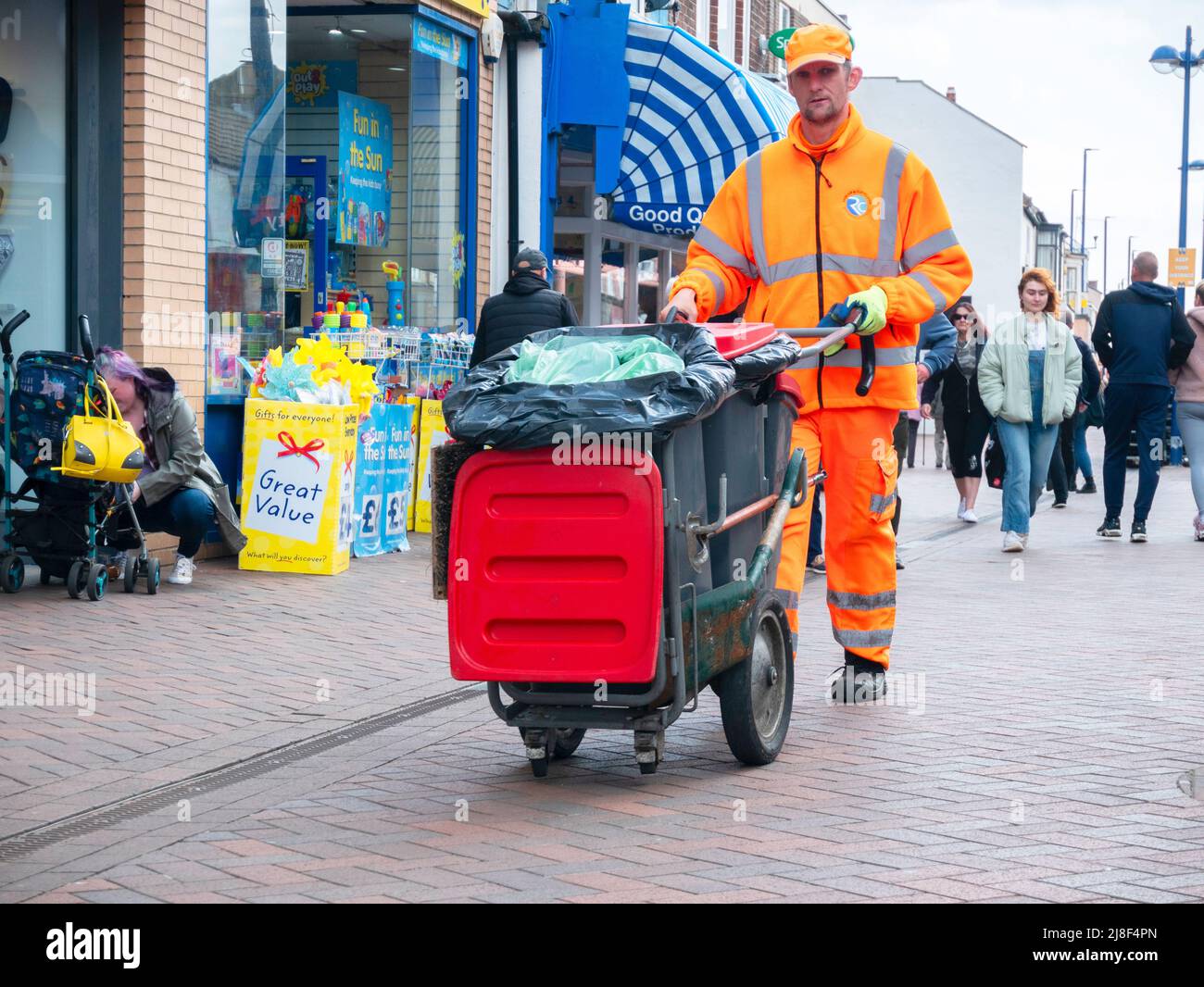 Straßenkehrmaschine mit seinem Ausrüstungshandwagen in Redcar High am Markttag Stockfoto