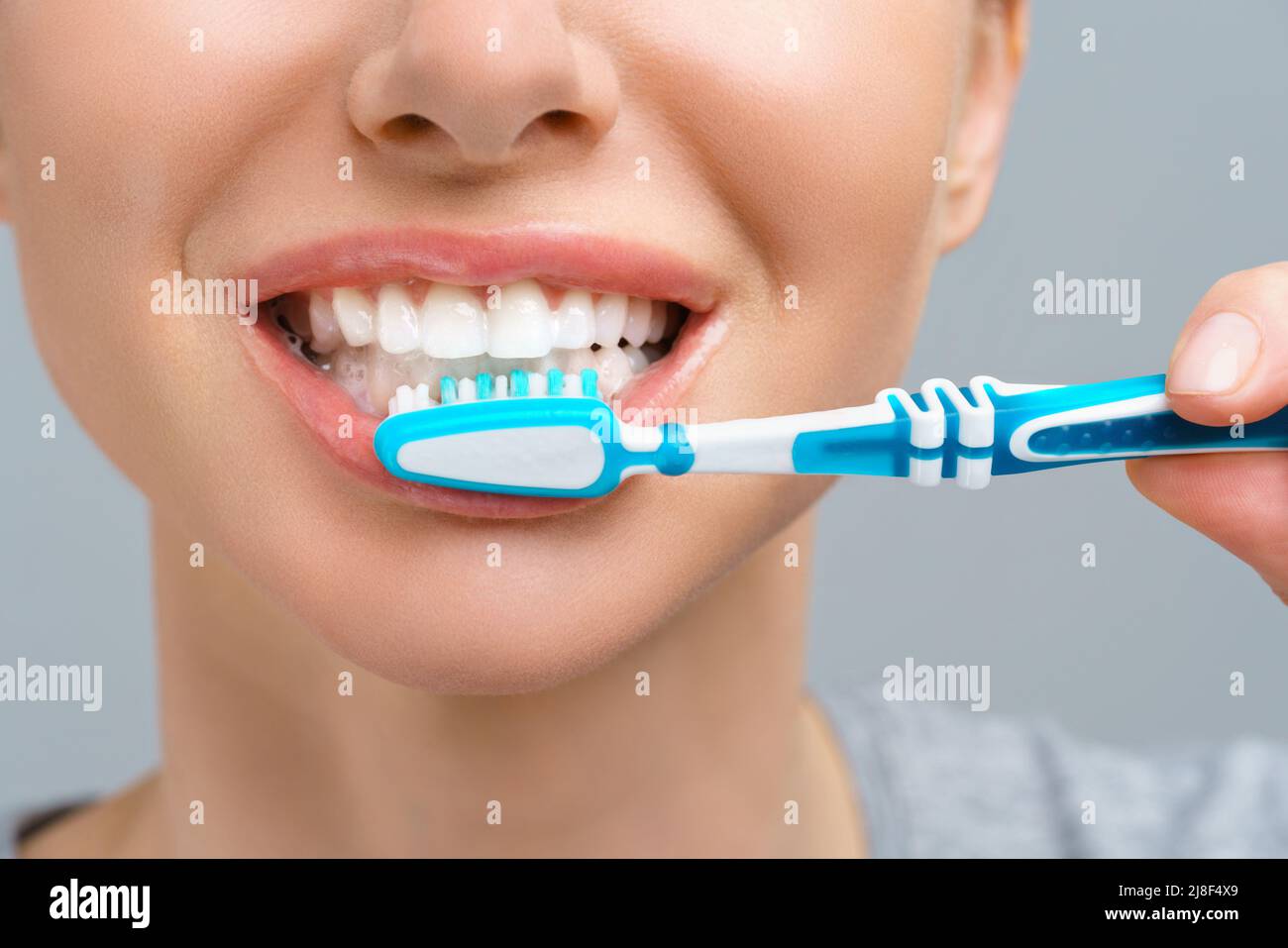 Wunderschöne lächelnde Frau Reinigung ihrer Zähne mit der Zahnbürste in einem Dental-Hygiene-Konzept. Isoliert auf weiss Stockfoto