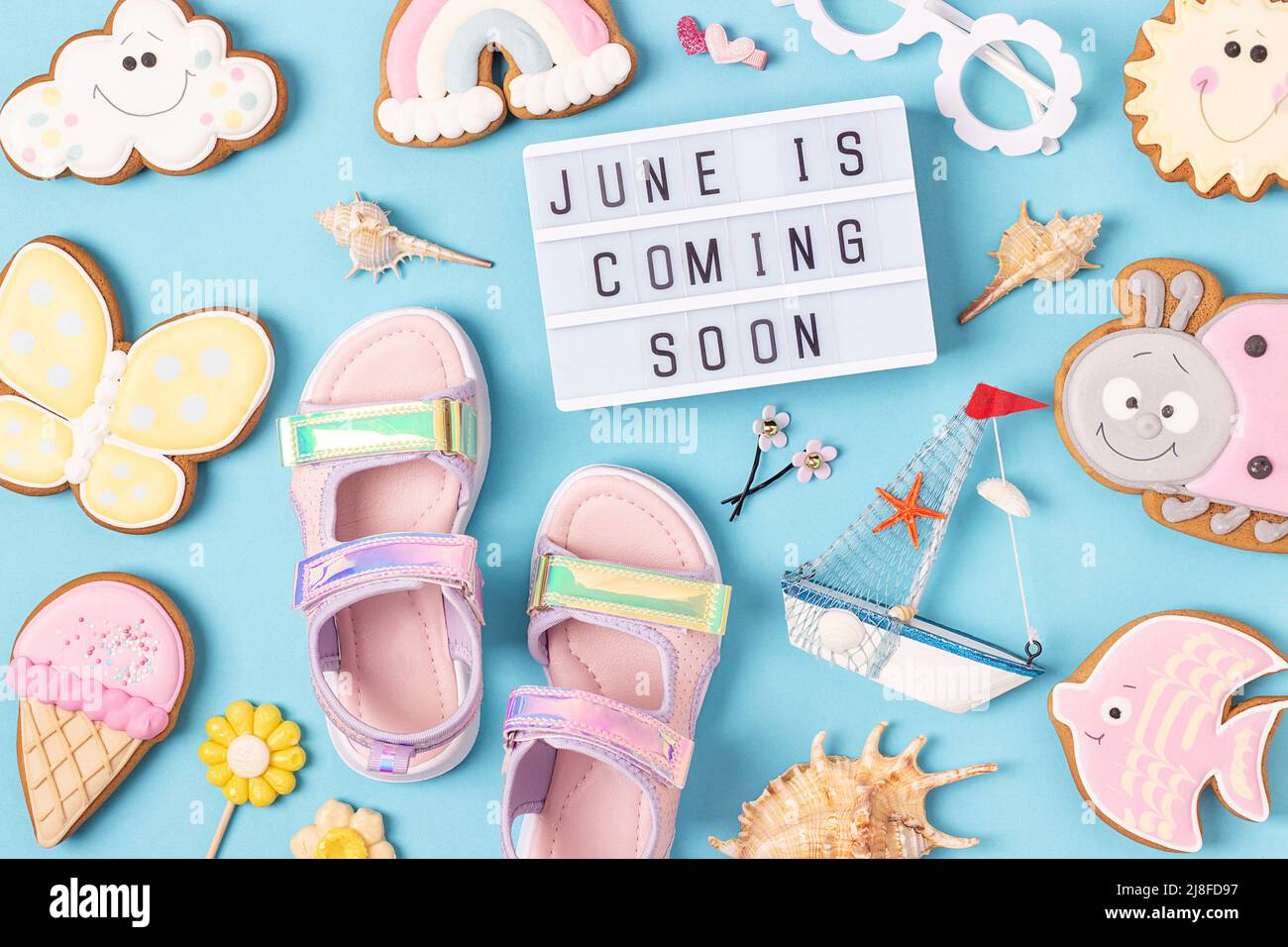 Der Sommer kommt. Motivationszitat auf Leuchtkasten und niedlichen Sommer-Symbolen auf blauem Hintergrund. Draufsicht, Flat Lay. Kreatives, inspirierendes Sommerkonzept Stockfoto