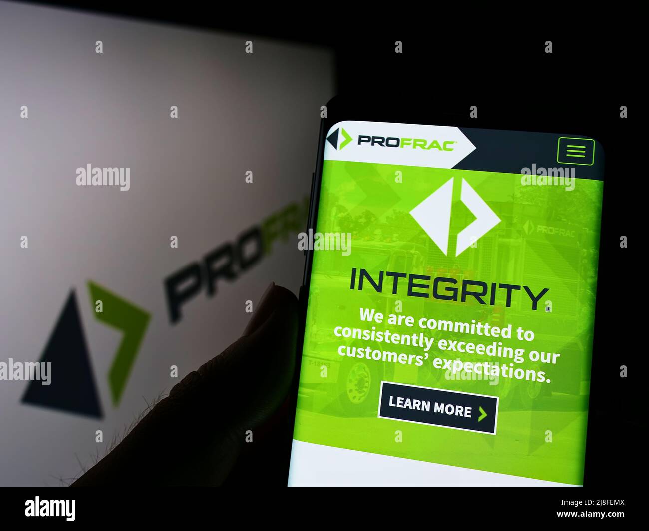 Person, die Mobiltelefon mit der Website des US-Öl- und Gasunternehmens ProFrac Services auf dem Bildschirm vor dem Logo hält. Konzentrieren Sie sich auf die Mitte des Telefondisplays. Stockfoto