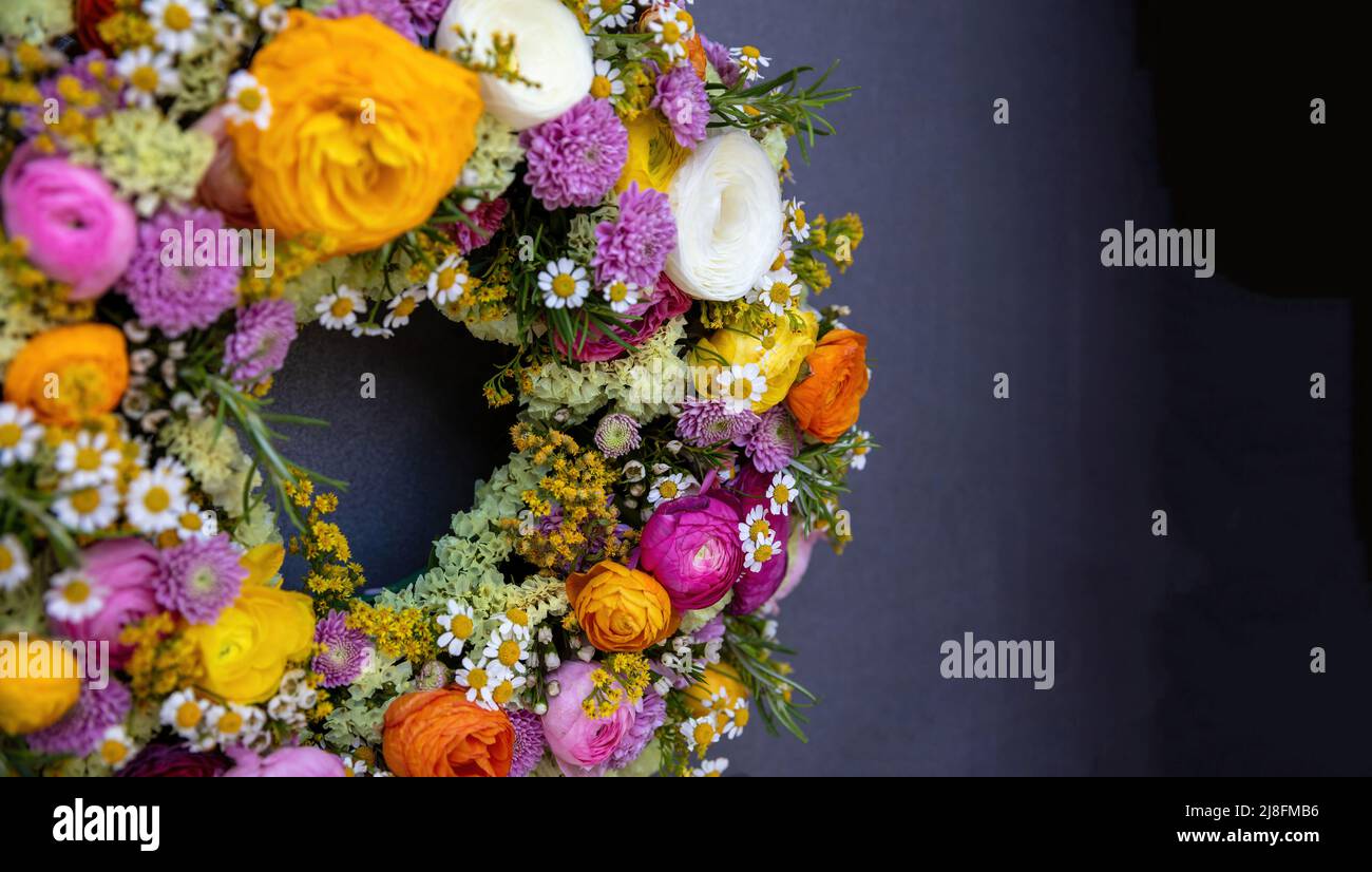Blumenkranz auf grauem Hintergrund. Frische Wildblumen und Kräuter, Dekoration, Nahaufnahme. Sonniger Frühlingstag. Frauen oder Mütter Tag Feier Stockfoto