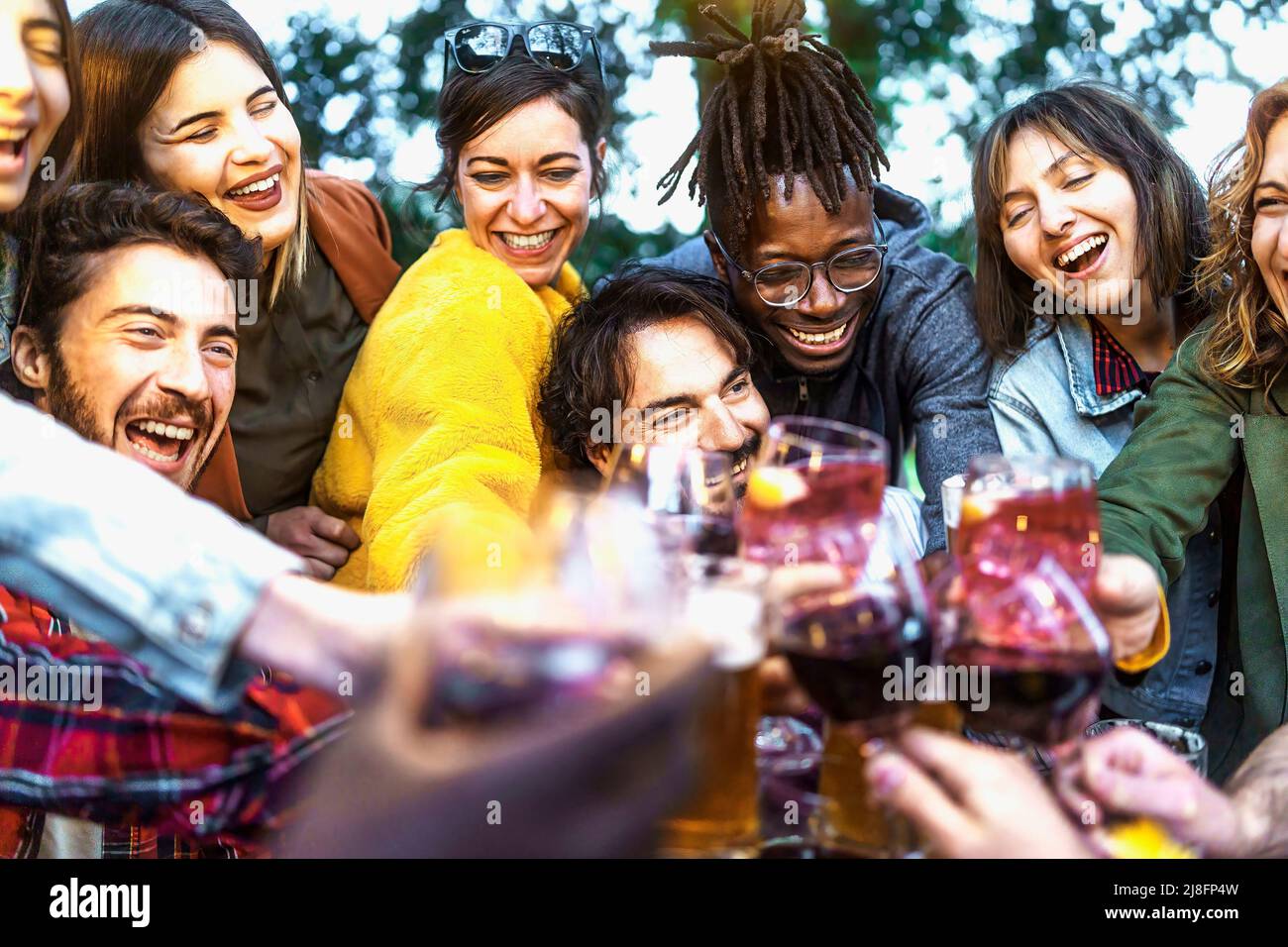 Multiethnische Gruppe von begeisterten jungen Menschen, die gemeinsam Wein und Bier auf der Geburtstagsfeier auf der Terrasse genießen - Lifestyle-Konzept der Multigeneration Stockfoto