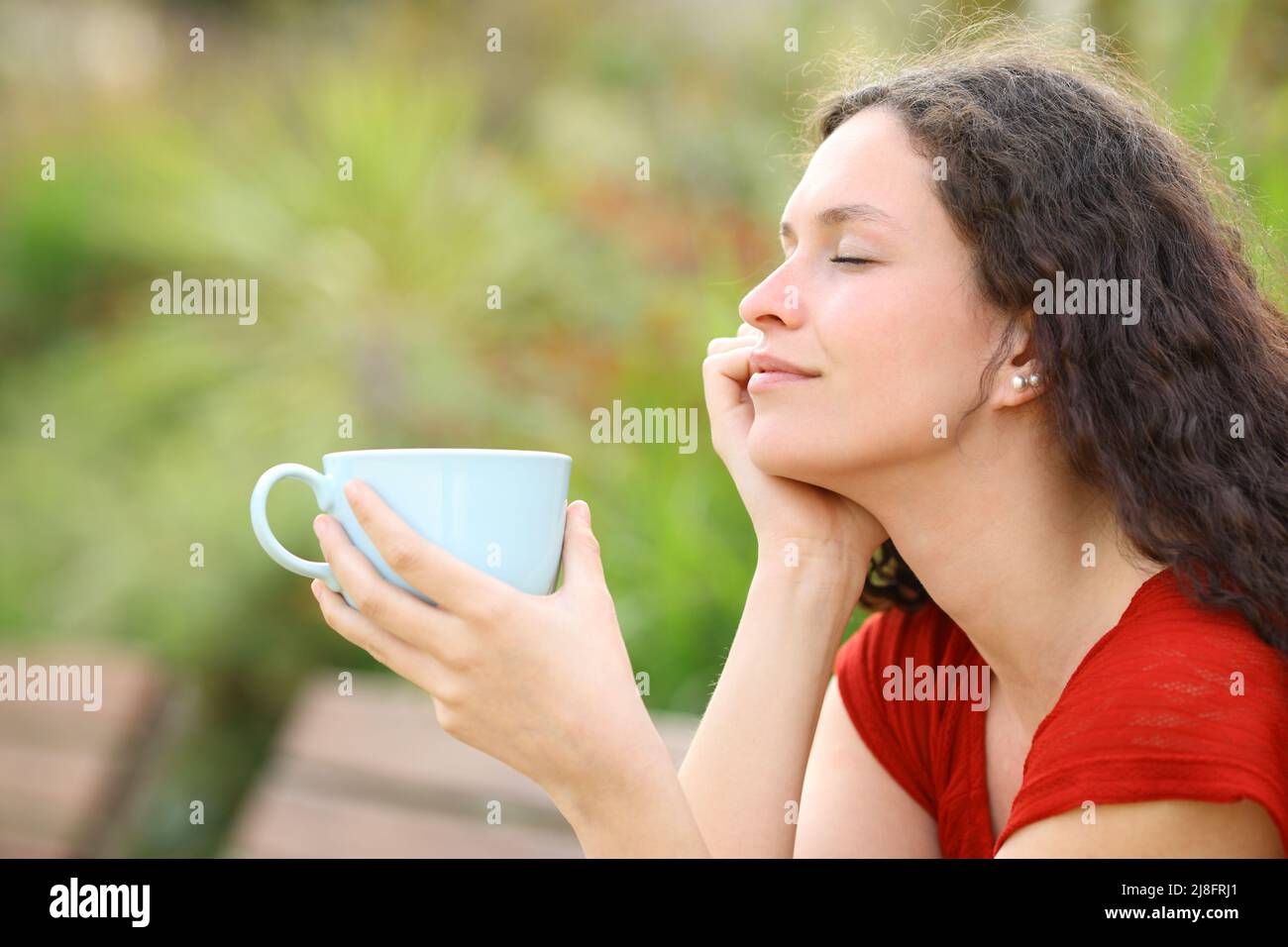 Profil einer entspannten Frau, die in einem Park eine Kaffeetasse hält Stockfoto