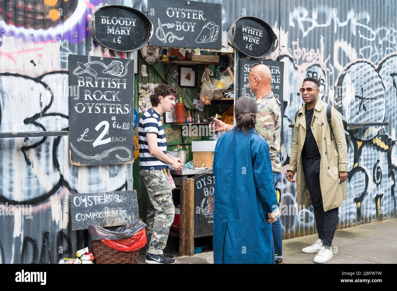 Ladenbesitzer und Kunde im Gespräch bei Oyster Boy, einem Austern-Verkaufsgeschäft in der Ezra Street, London E2, England, Großbritannien Stockfoto