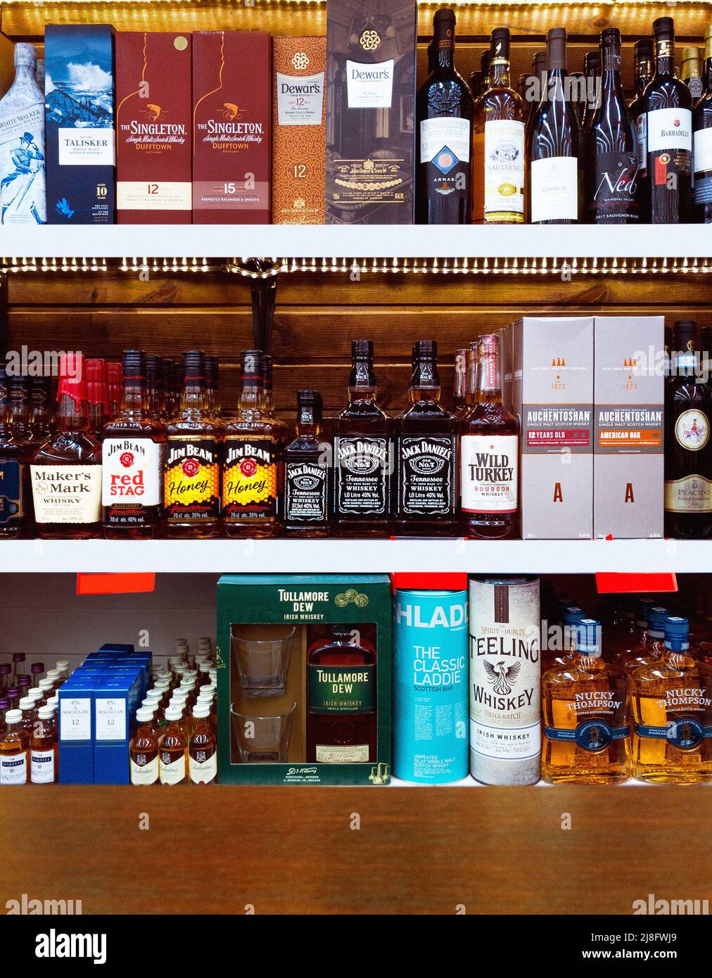 Whiskey-Sortiment berühmter Marken auf den Holzregalen des Weinladens Stockfoto