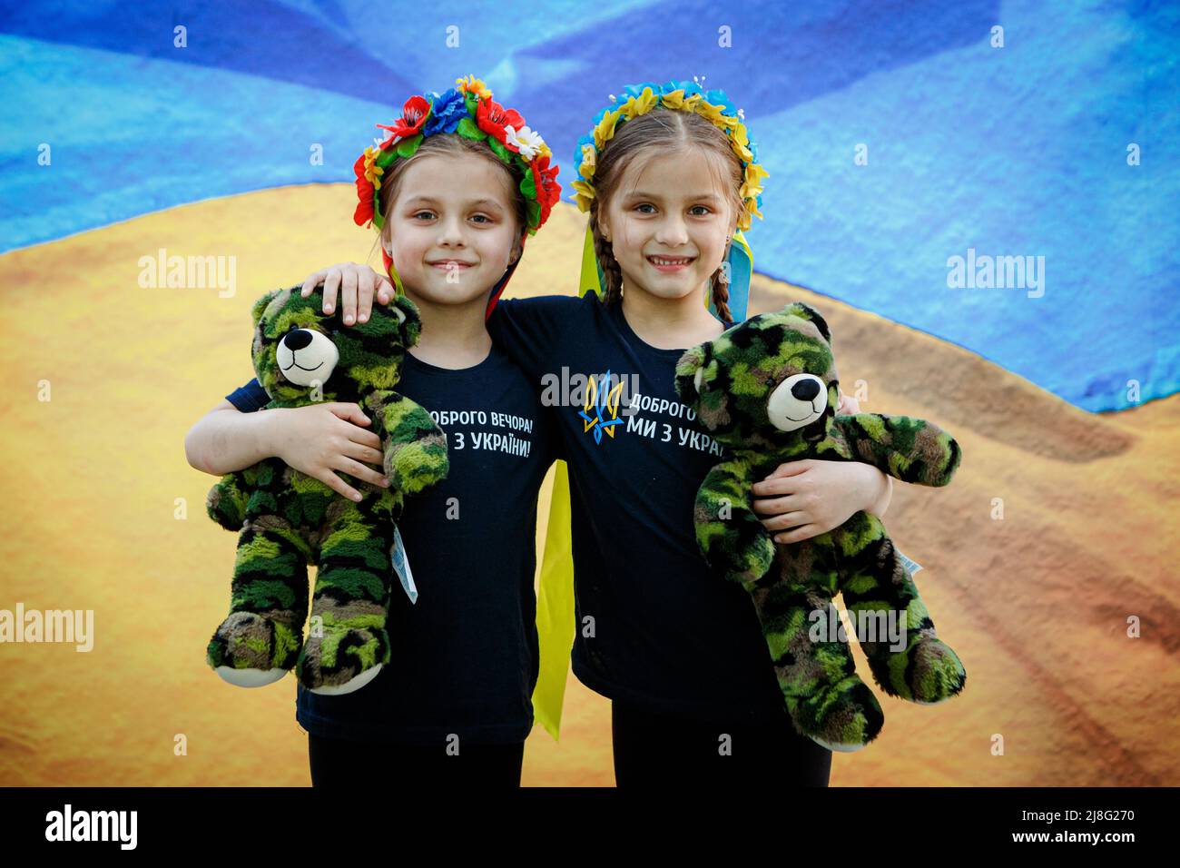 Non Exclusive: UZHHOROD, UKRAINE - 14. MAI 2022 - zwei Mädchen in Blumenkronen halten Tarnteddybären, wie lokale Fotografen die Porträts von machen Stockfoto