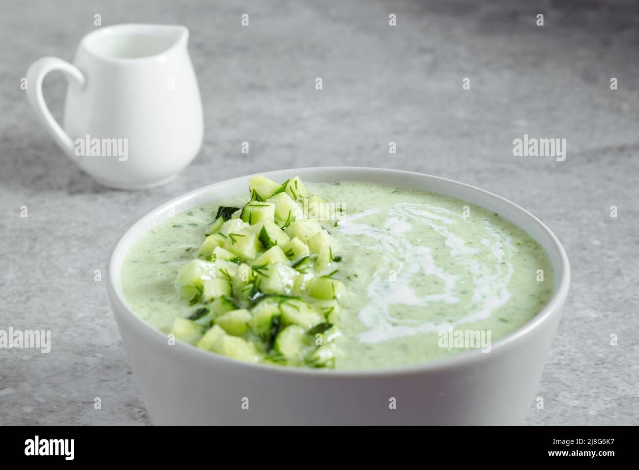 Gurke Gazpacho. Grüne frische kalte Sommersuppe auf grauem Hintergrund Stockfoto