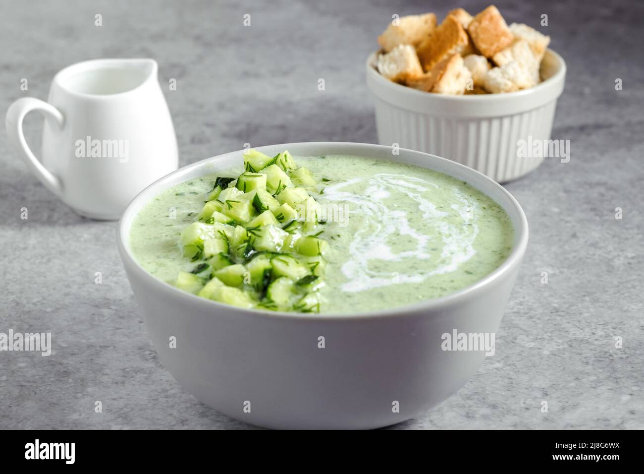 Gurke Gazpacho. Grüne frische kalte Sommersuppe auf grauem Hintergrund. Konzept der veganen Küche Stockfoto