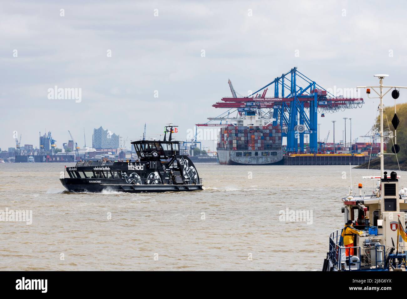 Hamburg, Deutschland - 5-3-2022: Die Stadt Hamburg vom Wasser der Elbe aus gesehen. Ein Containerschiff ist als Fährschiff am Terminal angedockt Stockfoto