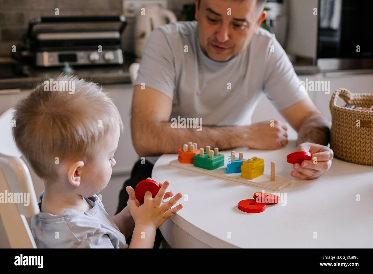 Vater und Kleinkind Junge Sohn spielen zusammen. Kleine niedliche Junge mit Papa sammeln bunte Sortierer. Familienleben, frühe Entwicklung von Kindern, Bildung Stockfoto