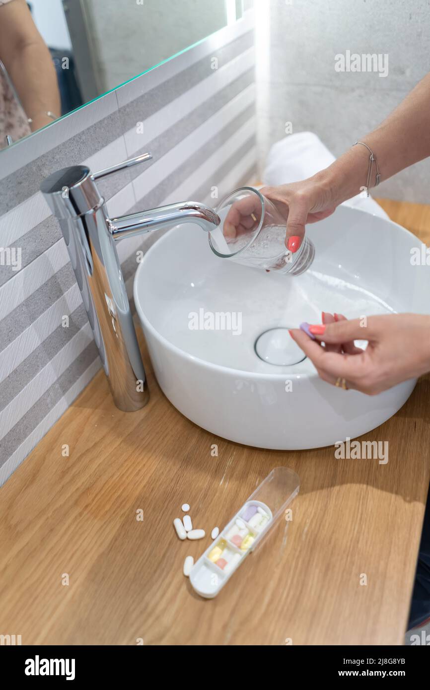 Frau nimmt Kopfschmerztabletten mit einem Glas Wasser in der Hand. Stockfoto