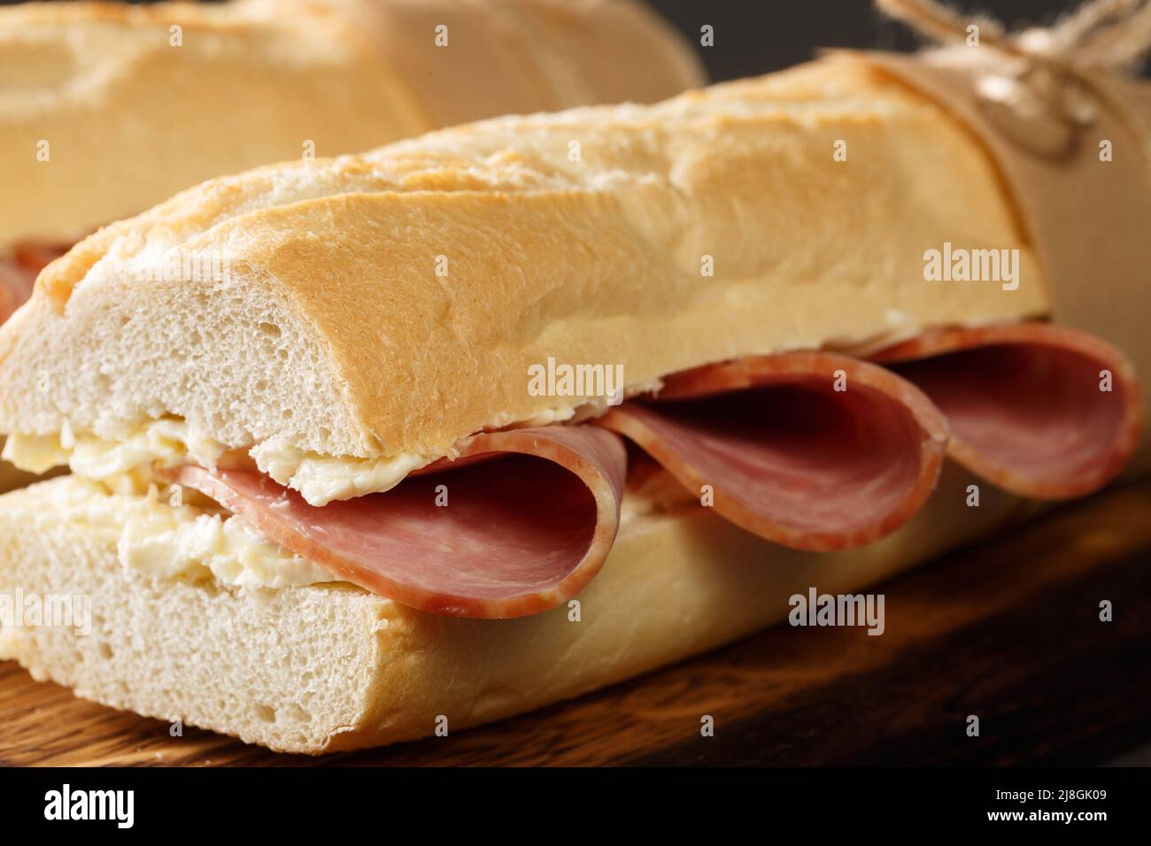 Französisches Sandwich knuspriges Baguette, leicht gesalzene Butter und dünn geschnittener Schinken, idealerweise Jambon de Paris in der Nähe auf dem Holzbrett. Horizontal Stockfoto