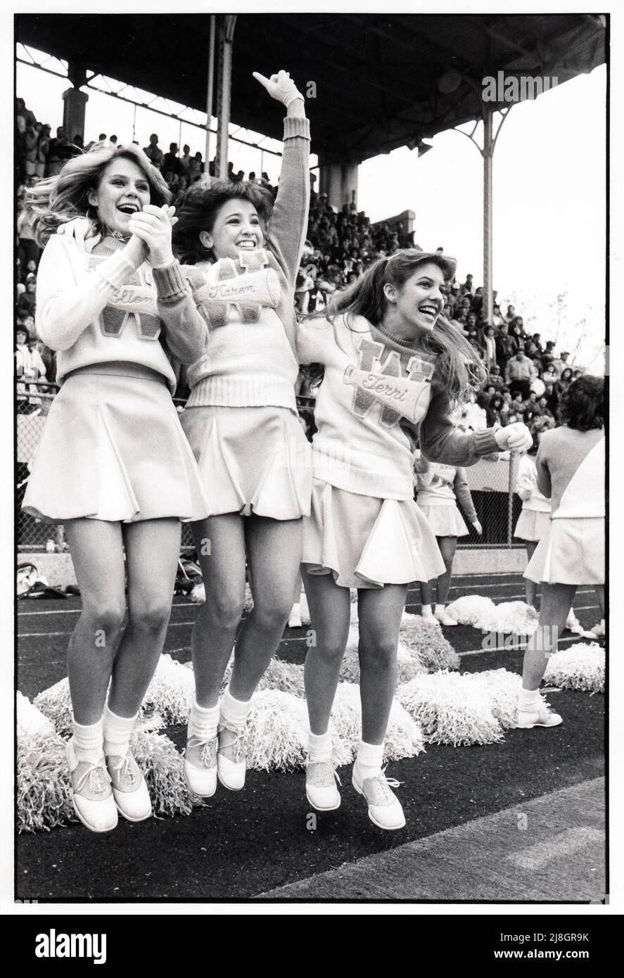 Cheerleader der High School reagieren auf einen Touchdown in einem Spiel gegen Midwood High im Midwood Field in Brooklyn, New York, um 1980. Stockfoto