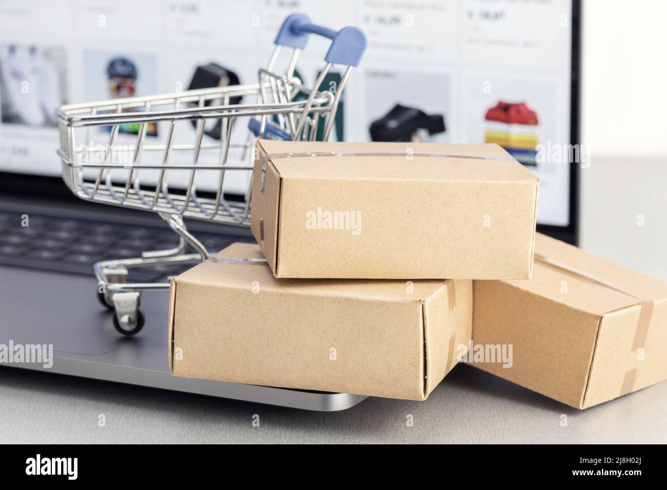 Online-Shopping-Konzept. Online-Shop-Kauf. Pappkartons und Warenkorb auf Laptop Stockfoto