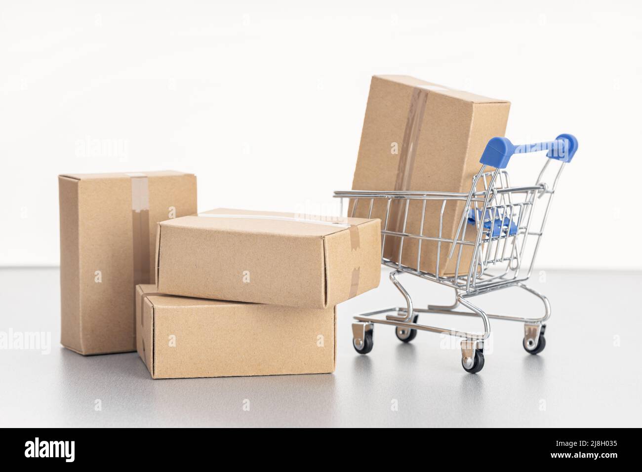 Leere Kartons und Einkaufswagen auf weißem Hintergrund mit Platz für Kopien. Verkaufs-, Rabatt-, Einkaufs- und Lieferkonzept Stockfoto