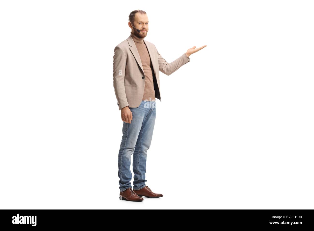 Ganzkörperaufnahme eines jungen Mannes mit einem Headset, das mit einer isolierten Hand auf weißem Hintergrund dargestellt wird Stockfoto