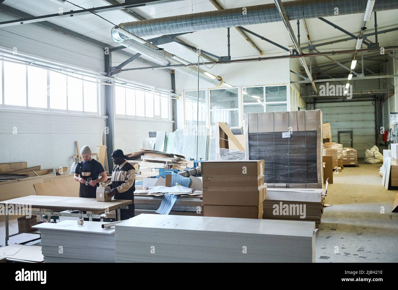 Bild des großen Lagers der Möbelproduktion mit den Arbeitern, die im Team arbeiten Stockfoto