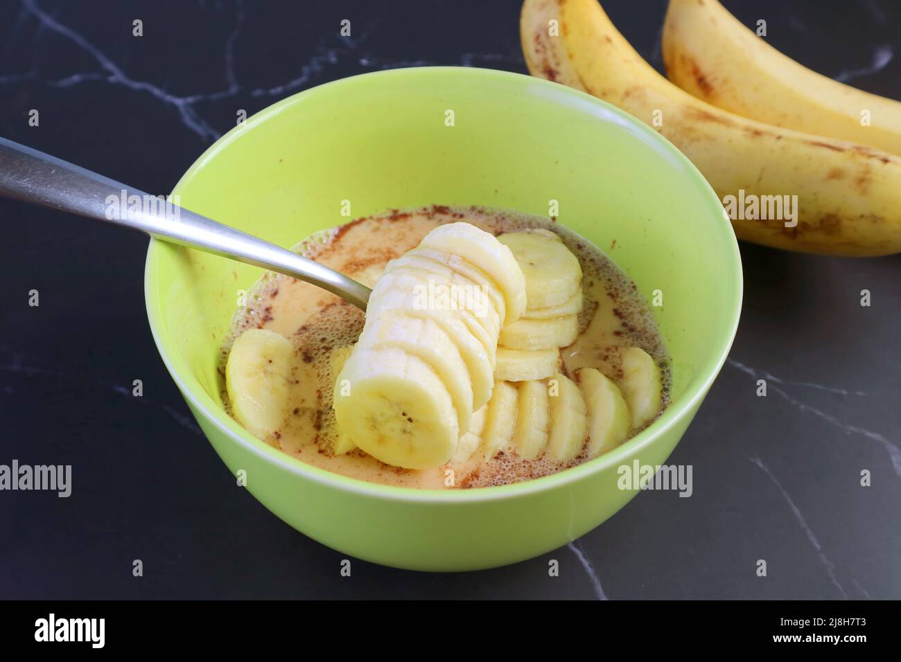 Scheiben frischer reifer Bananen in der Mischung zum Backen von Bananenbrotpudding Stockfoto