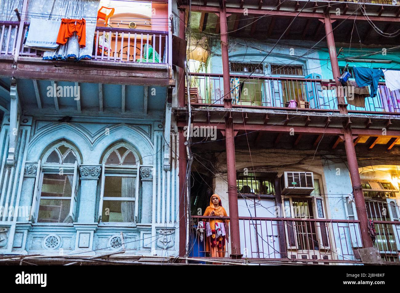 Mumbai, Maharashtra, Indien : Eine Frau blickt vom Balkon eines alten traditionellen Gebäudes auf die Straße. Stockfoto