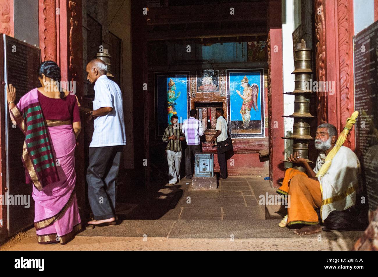 Udupi, Karnataka, Indien : Pilger stehen neben einem Bettler an einem Schrein des Krishna-Tempels aus dem 13. Jahrhundert. Der Tempel wurde von der lokalen Hindu sa gegründet Stockfoto