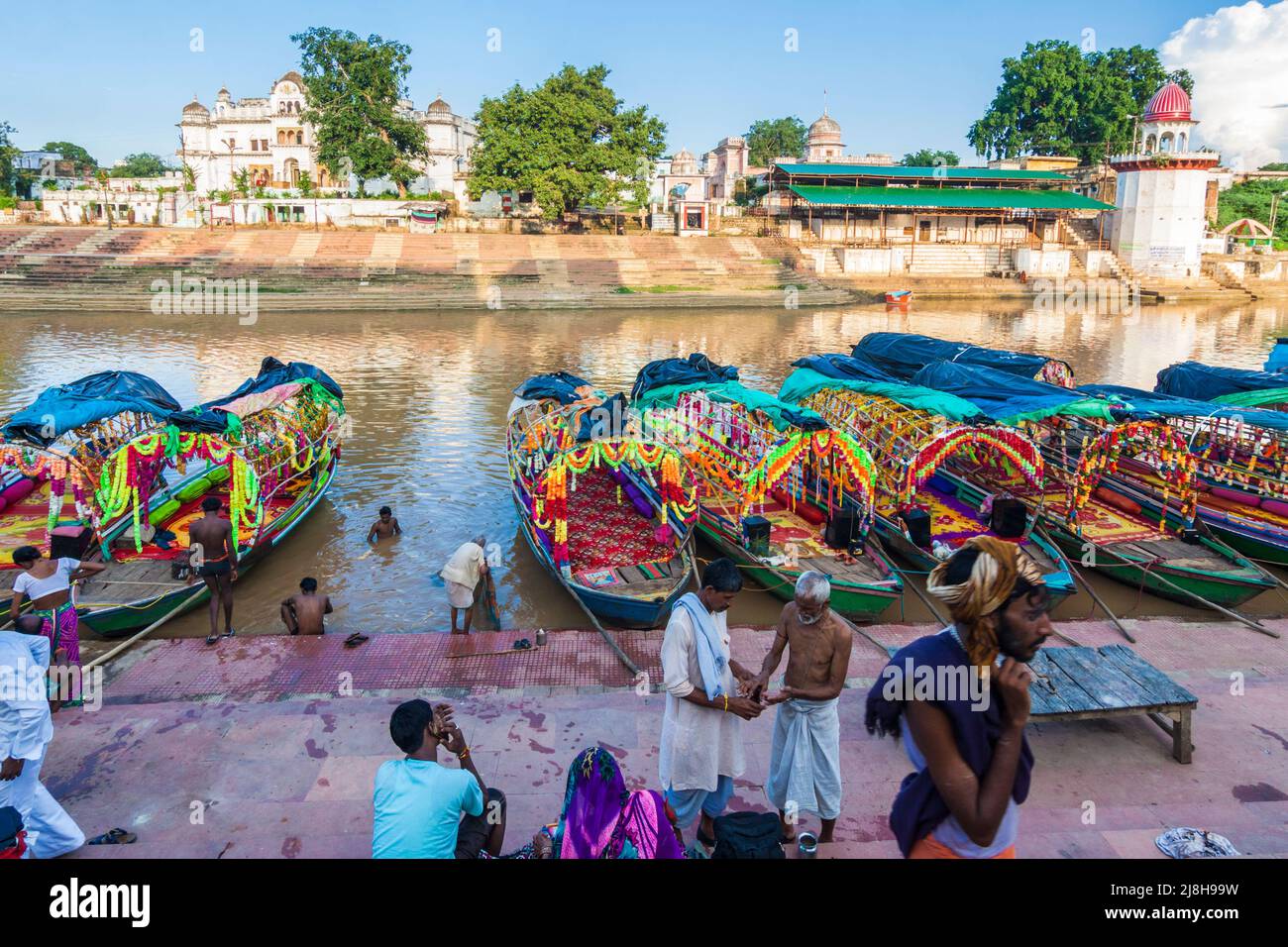 Chitrakoot, Madhya Pradesh, Indien : Eine Gruppe von Menschen steht an den bunten Booten, die sich in der Nähe der Stufen von Ramghat am Mandakini-Fluss säumen. Stockfoto