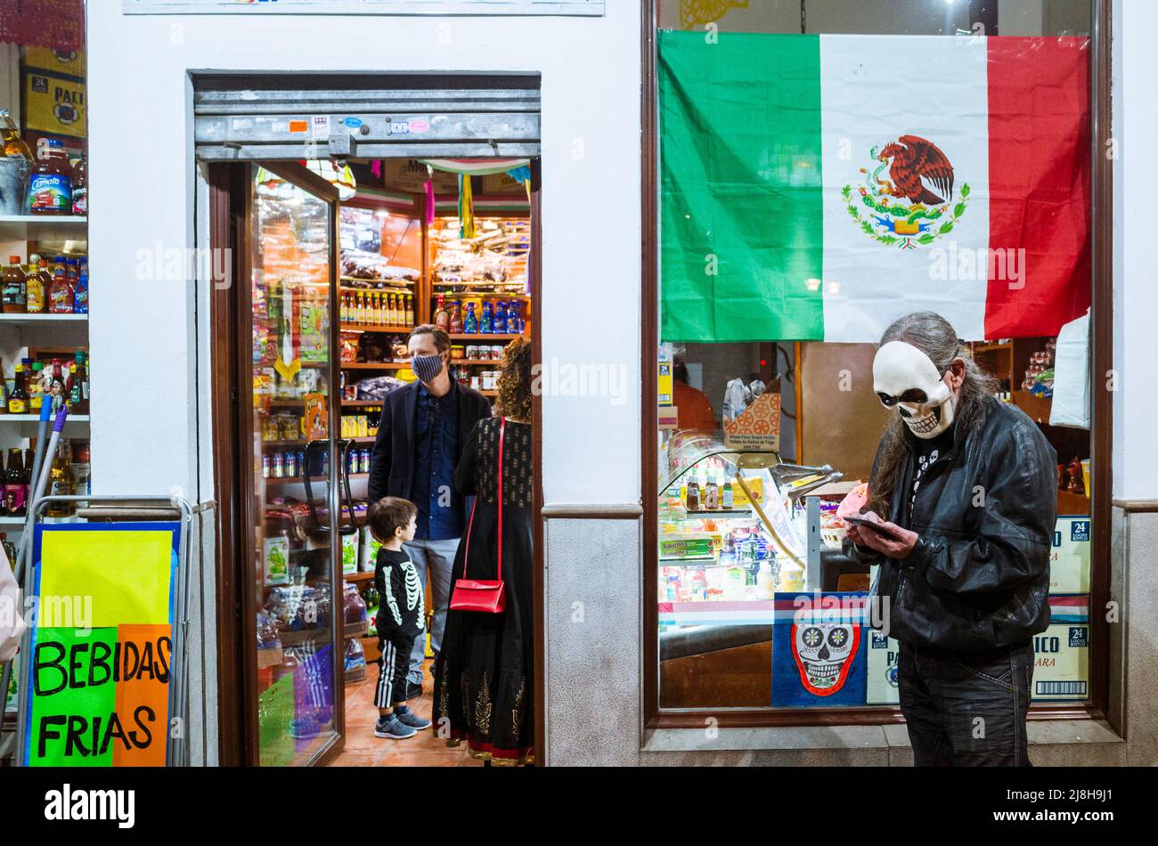 Granada, Andalusien, Spanien : am Tag der Toten steht ein mexikanischer Mann mit Totenkopfmaske vor einem mexikanischen Lebensmittelgeschäft. Stockfoto