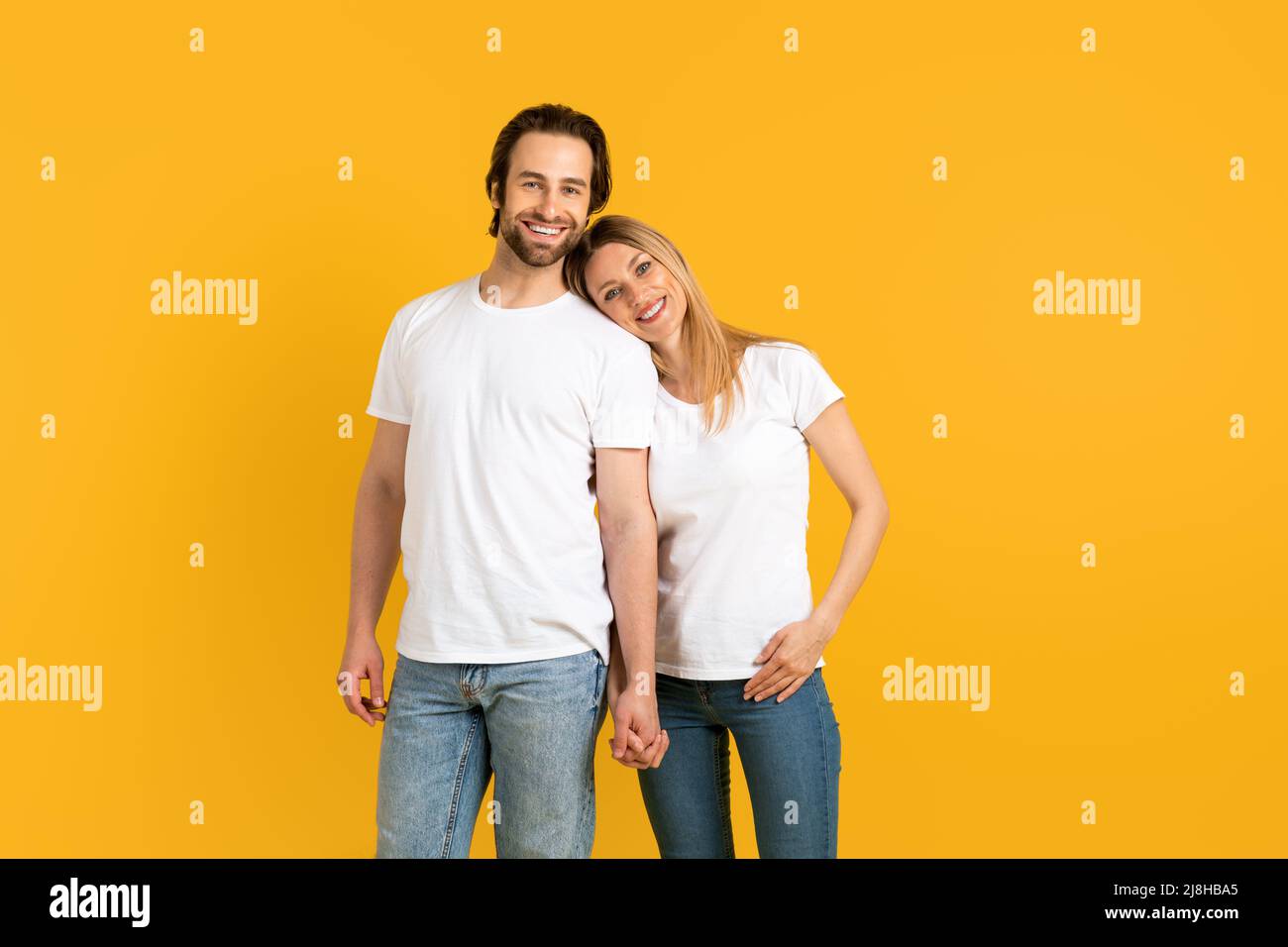 Fröhlicher, gutaussehender Mann und Frau aus dem tausendjährigen Kaukasus in weißen T-Shirts halten die Hände, genießen Sie den Moment Stockfoto